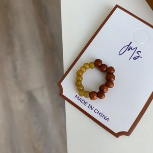 Détail macro d'une bague élastique en bois brun et perles de résine ambre sur carte