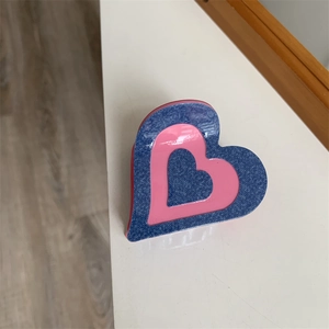 Détail d'une pince à cheveux en forme de cœur avec texture denim bleu et couche rose