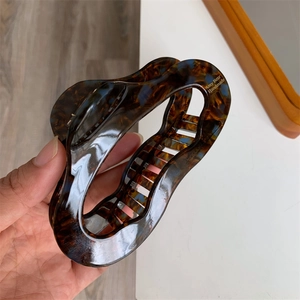 Macro shot of large tortoise shell acetate hair claw clip with golden handmade logo