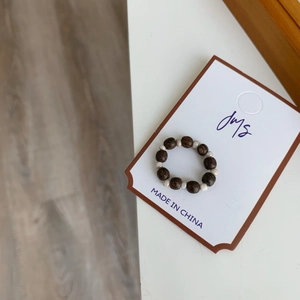Vue détaillée d'une bague ethnique en bois brun et perles crème sur carte de support