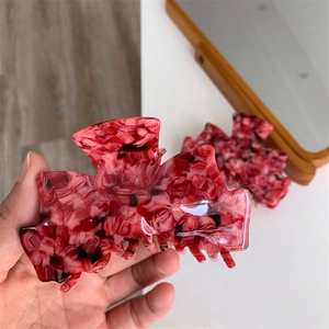 Vue détaillée de la pince à cheveux en acétate marbré rouge montrant le matériau épais de luxe