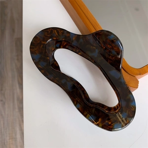Detailed close-up of tortoise shell pattern acetate hair claw clip with golden text