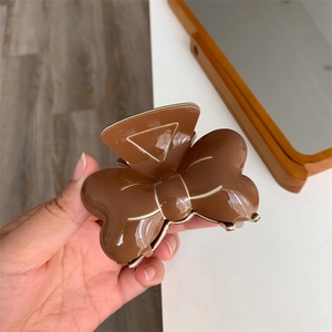 Détail de la pince à cheveux marron en résine avec bordure blanche et finition polie