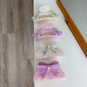 Detailed close-up of 4-piece purple and pastel acetate bow hair claw set for women