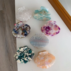 Détail de petites pinces à cheveux en acétate en forme de coquille avec strass brillants