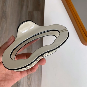 Close-up of wavy cream hair claw clip with black edges and handmade interior branding