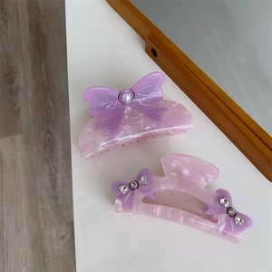 Detailed view of acetic acid hair claws with purple bows, pearls, and rhinestones