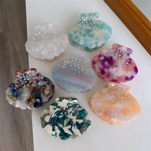 Détail de pinces à cheveux en acétate en forme de coquillage avec strass étincelants