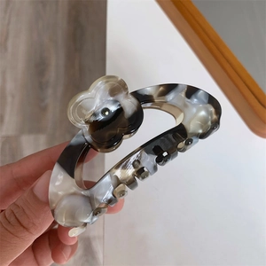 Detail of marble pattern acetate hair claw with delicate clover floral decorative elements