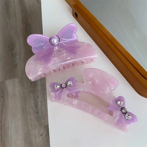 Close-up of pink marble acrylic hair clips with purple ribbon bows and pearl accents