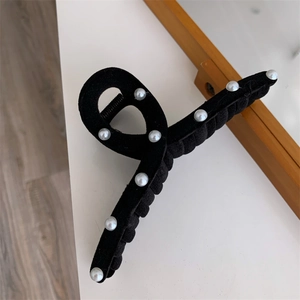 Detail view of black velvet hair claw clip with elegant pearl embellishments and a twisted design