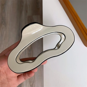 Detail view of a large cream acetate shark hair claw clip with black wavy edge accents
