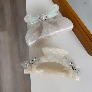 Close-up of elegant cream acetate hair claws with pearls and rhinestone butterflies