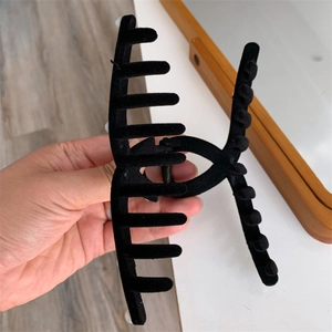 Close-up of a large black flocked hair claw clip with velvet texture for thick hair