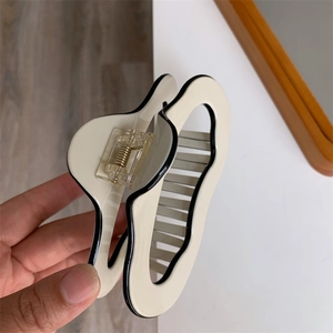 Detail view of large cream acetic acid shark hair claw clip with black contrast edges