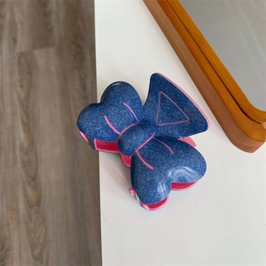 Détail d'une pince à cheveux avec nœud créatif, texture denim bleu et contraste rose