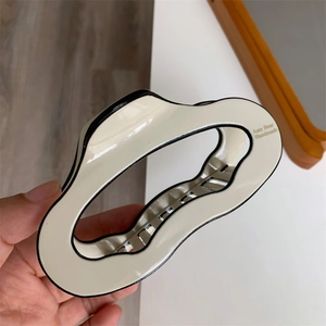 Detailed view of a cream wavy hair claw with black edges and Amy Bear Handmade text