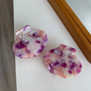 Vue détaillée de pinces à cheveux en acétate en forme de coquillage avec strass et marbre