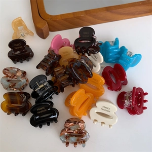 Gros plan sur de mini pinces à cheveux en acétate coloré avec motifs marbrés et ressort