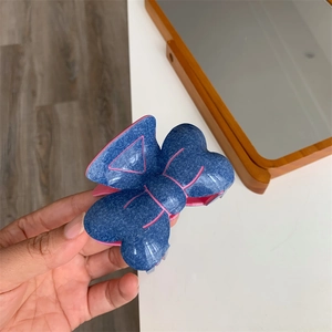 Détail de pince à cheveux avec nœud bouffant en denim bleu et bordures roses