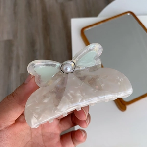 Close-up of marble pattern hair claw with translucent bow and pearl detail