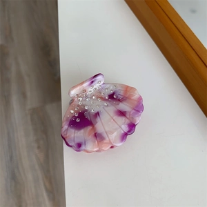 Détail de la pince à cheveux en acétate en forme de coquillage avec strass et effet marbré
