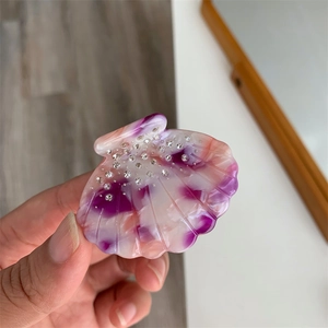 Détail d'une pince à cheveux en acétate en forme de coquillage avec motif marbré et strass