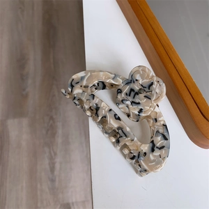 Detail showing the floral acetate hair claw clip with marble tortoiseshell texture and metal spring