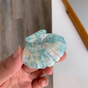 Détail d'une pince à cheveux en acétate en forme de coquillage marbré bleu et strass