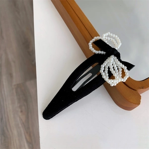 Detailed view of a black velvet drop hair clip with elegant faux pearl bow decoration