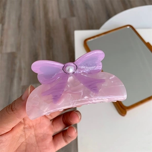 Detail of purple acetate hair claw with marble texture and pearl bow embellishment