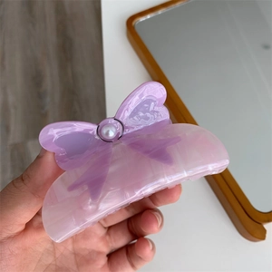 Detailed view of a purple marbled acetate hair claw clip with bow and pearl embellishment