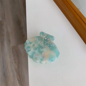 Vue détaillée d'une pince à cheveux en forme de coquillage avec texture marbrée et cristaux