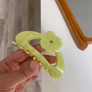 Detail of flower hair claw clip with yellow marble acetate finish and green gemstone center