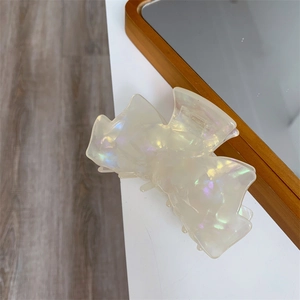 Vue détaillée d'une pince à cheveux nœud nacrée irisée aux finitions brillantes