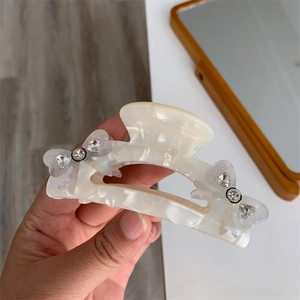 Close-up of marble acetate hair claw with crystal bow accents held in hand