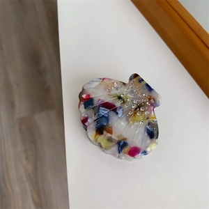 Détail d'une pince à cheveux en acétate en forme de coquillage avec strass brillants