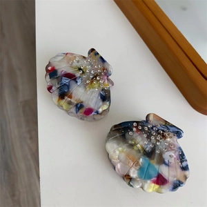 Détail des pinces à cheveux en acétate en forme de coquille avec texture marbrée et strass