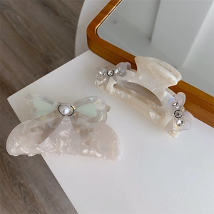 Close-up of acetic acid hair clips with marble texture and elegant pearl bow details