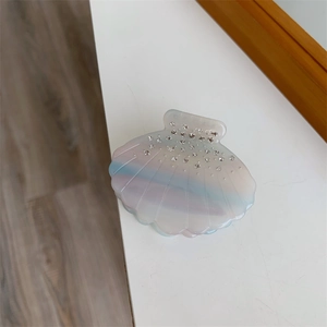 Détail d'une pince à cheveux en forme de coquille aux couleurs dégradées et strass brillants