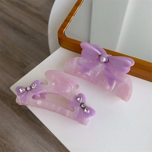 Detailed macro of thick purple marble acetate hair claws with bow and pearl accents