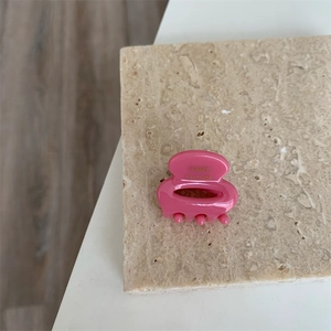 Détail d'une mini pince à cheveux en acétate rose vif avec lettrage doré fait main