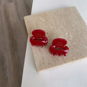 Détail de mini pinces à cheveux en acétate rouge avec inscription faite à la main