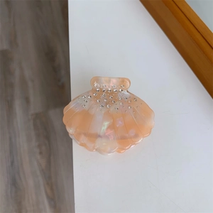 Détail macro de la pince à cheveux en acétate rose pêche marbré avec strass incrustés