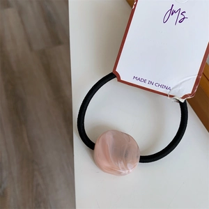 Close-up of pink marble resin bead on black high-elastic hair tie with branded tag