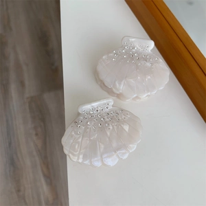 Gros plan de pinces à cheveux en acétate en forme de coquillage avec strass et fini nacré