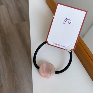 Detail of pink marble pattern resin bead on a high-elasticity black hair tie