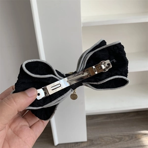 Detail view of the metal spring clip and golden pendant on a fabric bow hair clip
