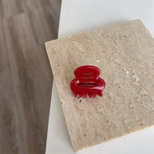 Détail d'une pince à cheveux en acétate rouge avec lettrage doré France Handmade