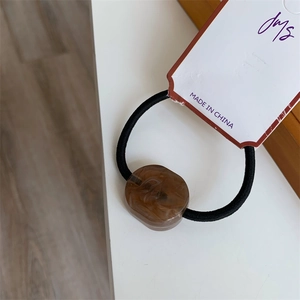 Detail of high elastic hair tie with brown marbled resin bead and branded tag